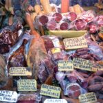 Mercato di Bologna con bancarelle di cibo e visitatori entusiasti che esplorano le specialità locali.