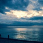 Spiaggia deserta d'inverno, onde calme e cielo grigio, un paesaggio che invita alla riflessione e alla serenità.