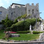 Borgo di Venzone con mummie esposte e dettagli della ricostruzione storica in pietra.