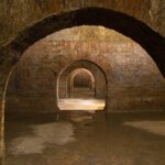 Vista della città sotterranea di Napoli con passaggi antichi e affreschi storici.