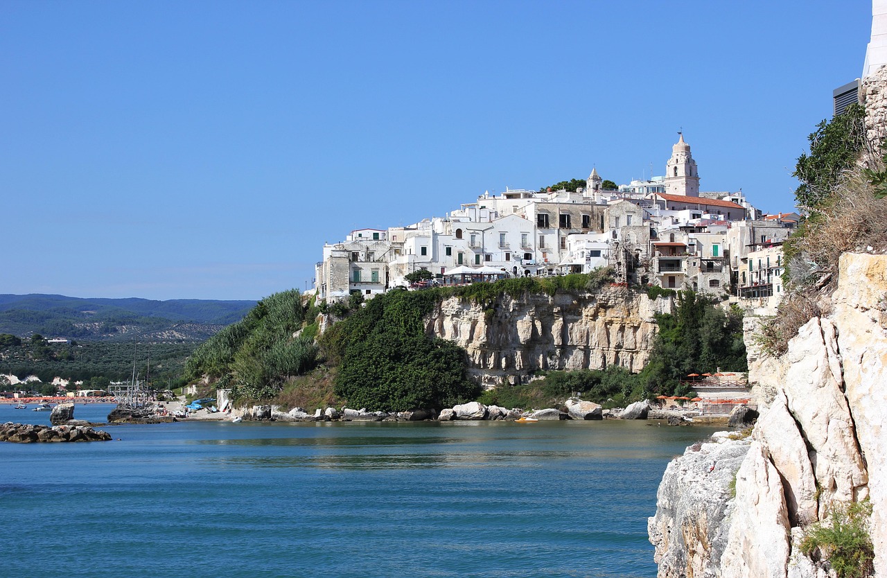 Vista panoramica del borgo di Sperlonga con case bianche e la villa di Tiberio sullo sfondo del mare.