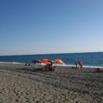 Spiaggia segreta in Calabria con sabbia bianca e acque cristalline, vista panoramica e accesso suggestivo.