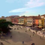 Piazza storica di Treviso con bancarelle colorate del mercato, affollata di visitatori e atmosfera vivace.