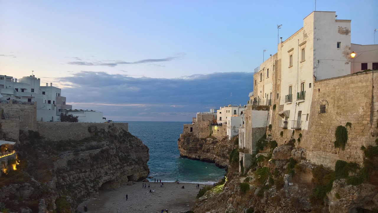 Spiaggia di Puglia affollata, sabbia dorata e mare cristallino sotto un cielo azzurro.